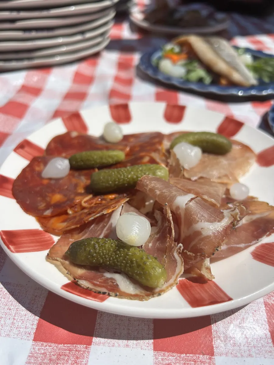 Assiette de charcuterie et cornichons sur nappe à carreaux